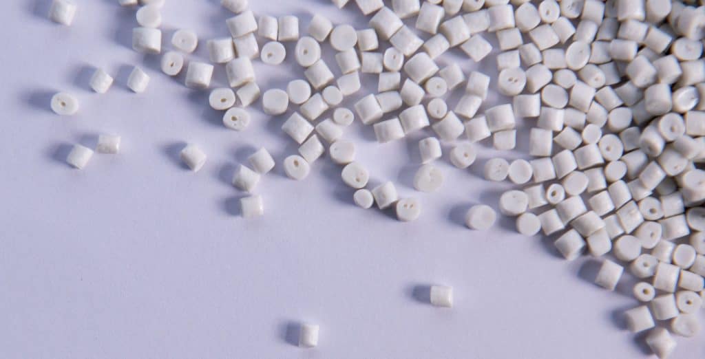 Verstreute Polypropylene (PP) Plastik Pellets auf einer grauen Fläche